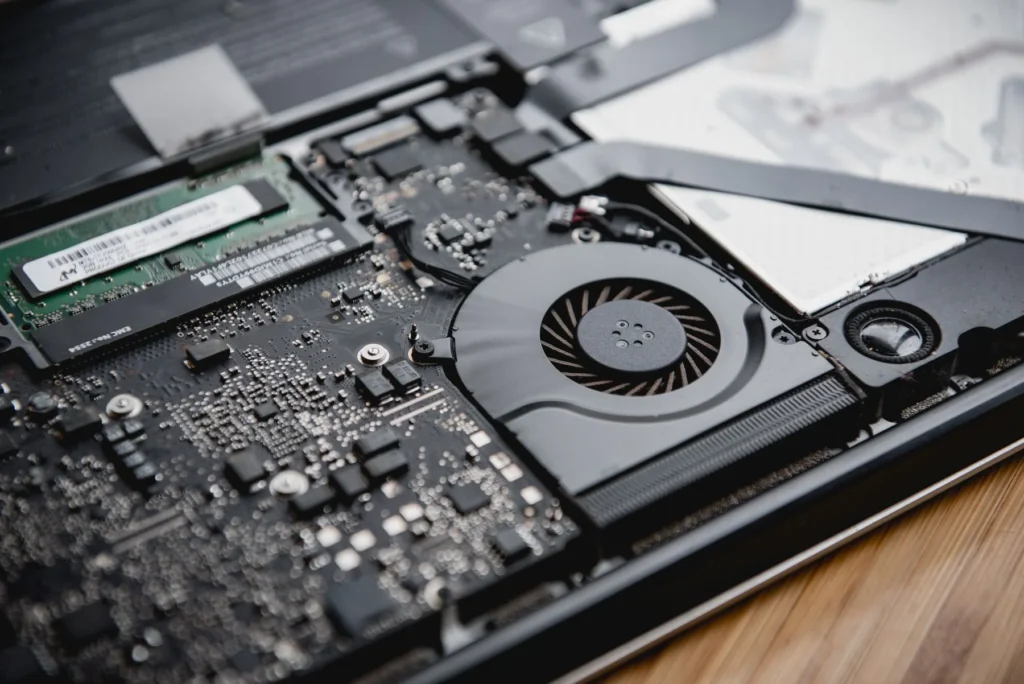 Close view inside a laptop showing its cooling fan, circuit board, and installed memory module.