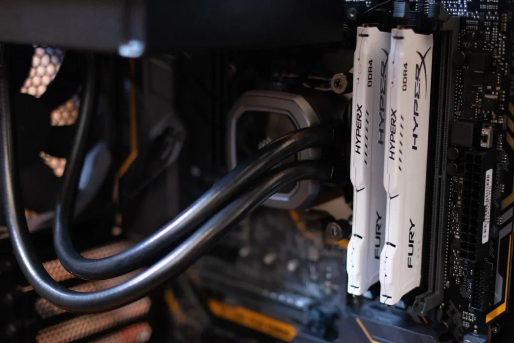 White memory modules beside black liquid-cooling tubes and a processor block inside a desktop computer.