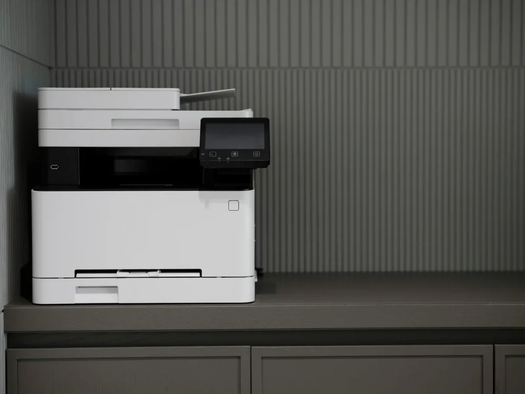 A white multifunction printer and copier with paper trays and a document feeder.