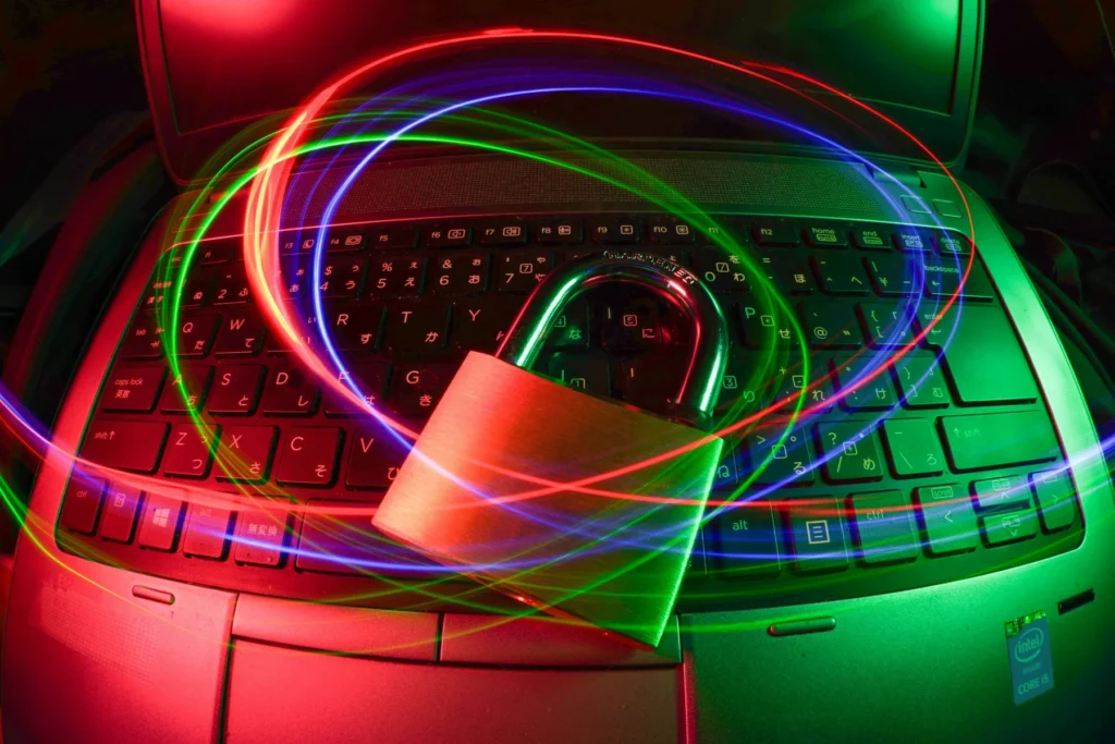 A brass padlock on a laptop keyboard surrounded by red, green, and blue light trails.