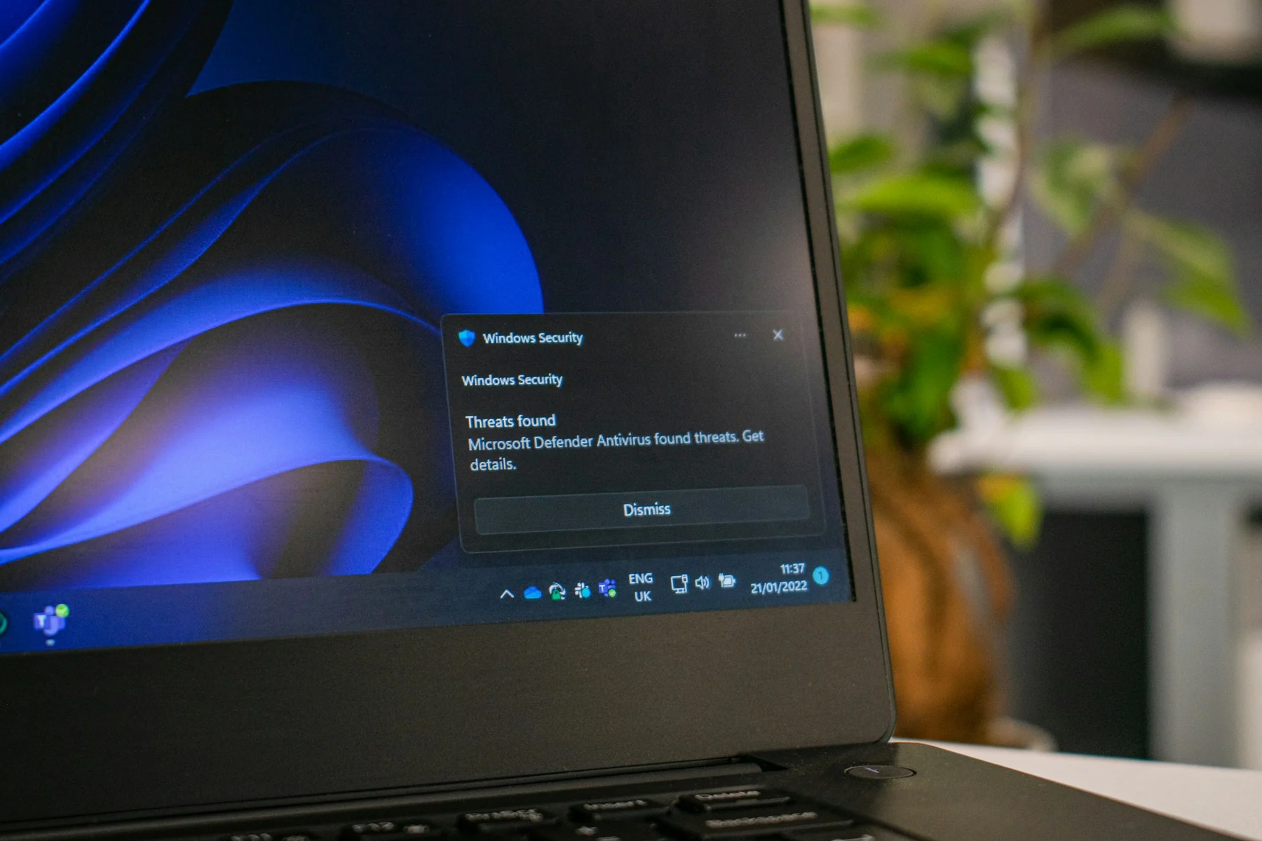 A laptop displaying a Windows Security notification that Microsoft Defender Antivirus found threats.
